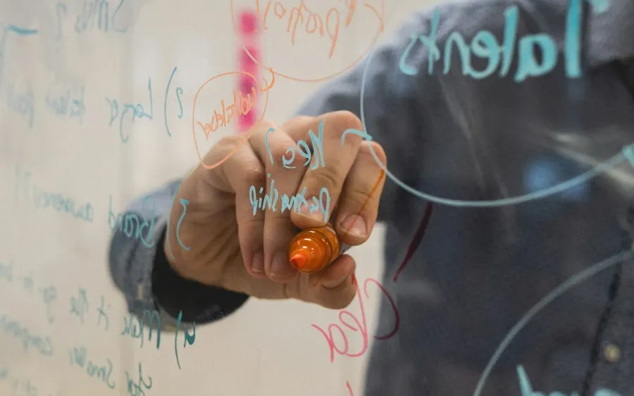 Person drawing a test plan on a glass whiteboard